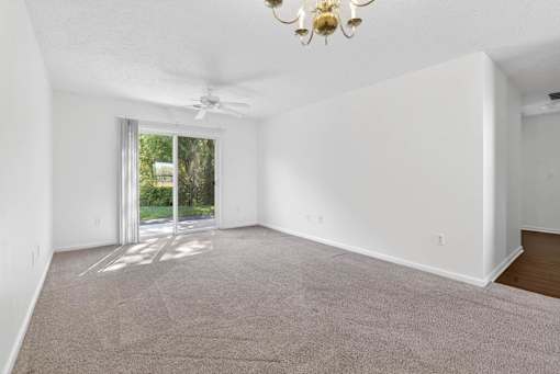 A room with a carpeted floor and a ceiling fan.