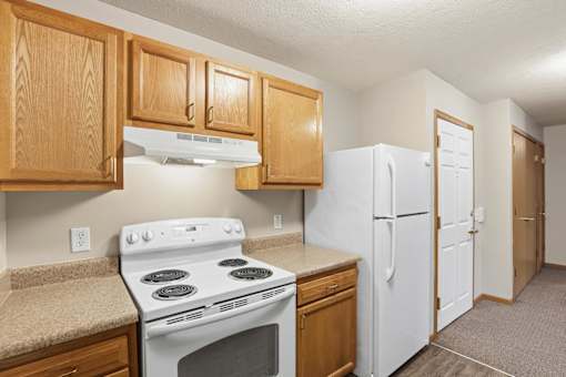A kitchen with a white stove and refrigerator.