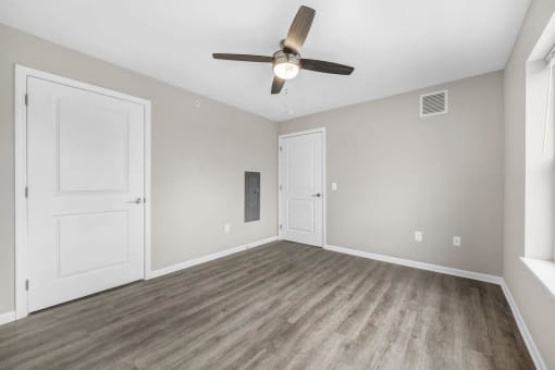 an empty living room with a ceiling fan and white doors
