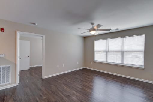 an empty room with a ceiling fan and a large window