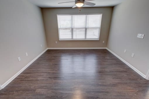 an empty room with a ceiling fan and a window