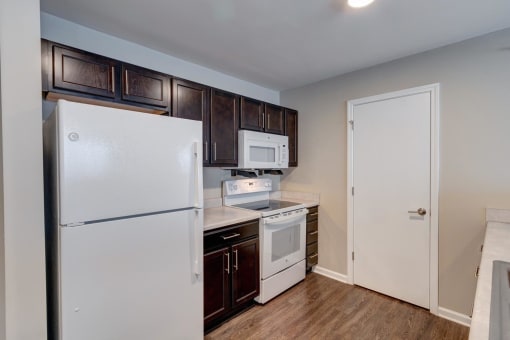 a kitchen with dark wood cabinets and white appliances