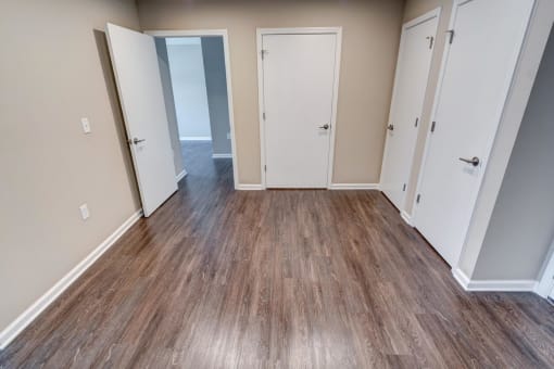 a bedroom with a hardwood floor and several doors