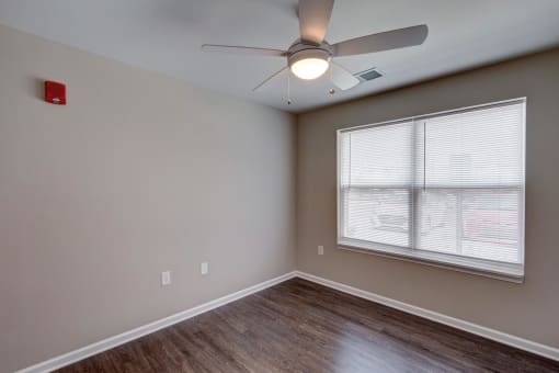 an empty bedroom with a ceiling fan and a large window