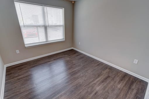 a bedroom with hardwood floors and a window