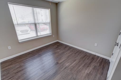 a bedroom with hardwood floors and a large window