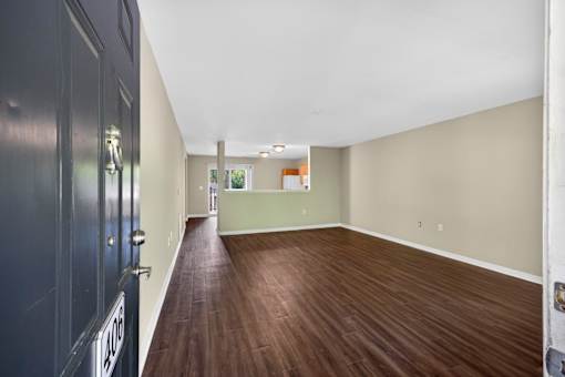A room with a dark wood floor and white walls.