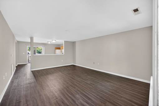 A large empty room with wood flooring and white walls.