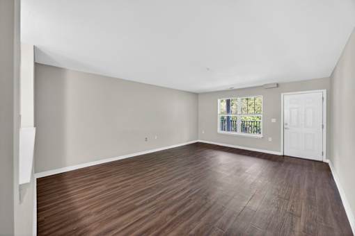 Empty room with wooden flooring and white walls.