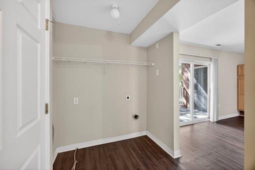 A room with a white door, a window, and a wooden floor.