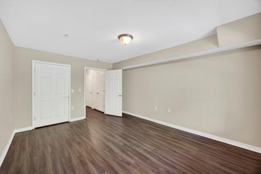 A room with a white ceiling and wooden flooring with two white doors.