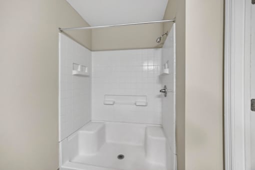 A white bathroom with a shower stall and a toilet.