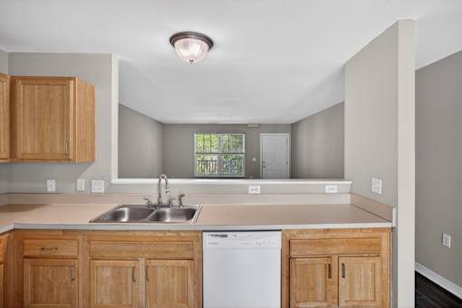 A kitchen with wooden cabinets and a white dishwasher.