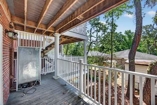 A wooden deck with a white railing and a grill on it.