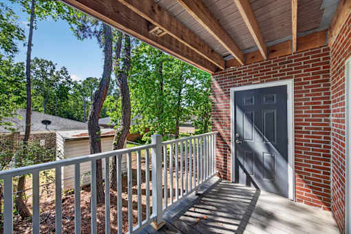 A wooden deck with a metal railing and a grey door.