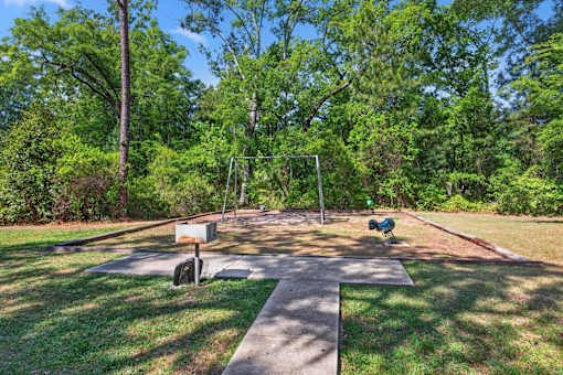 A park with a swing set and a basketball hoop.