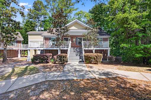 A house with a front porch and a tree in front.