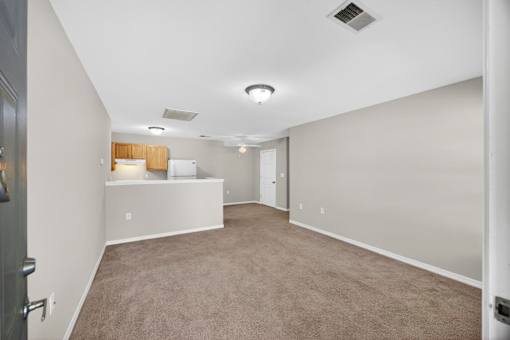 A spacious room with a carpeted floor and a ceiling fan.