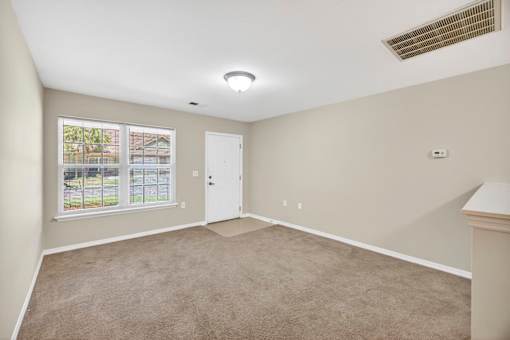 A room with a carpeted floor and a window showing an outdoor pool.