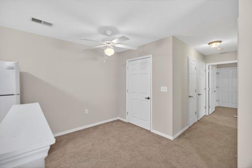 A room with a white ceiling fan and carpeted floor.