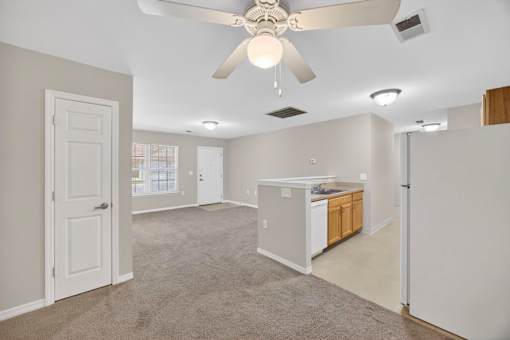 A spacious room with a ceiling fan and a kitchenette.