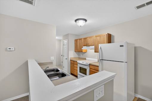 A kitchen with white appliances and wooden cabinets.