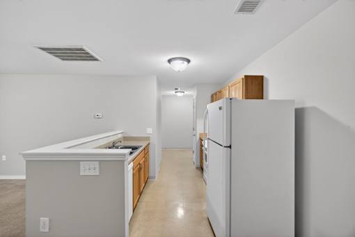 A kitchen with a refrigerator, sink, and cabinets.