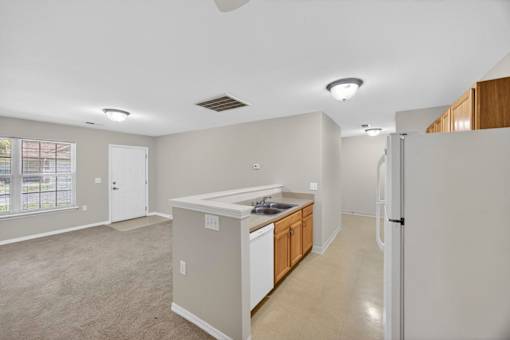 A kitchen area with a sink, refrigerator, and cabinets.