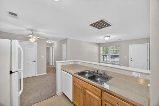 A kitchen with a sink, refrigerator, and cabinets.