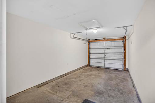 A garage with a white door and a concrete floor.