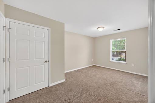 A room with a white door and carpeted floor.