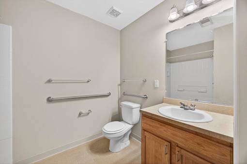 A white toilet sits in a bathroom next to a sink.