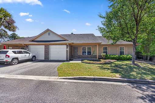 A house with a white garage door and a tree in front.