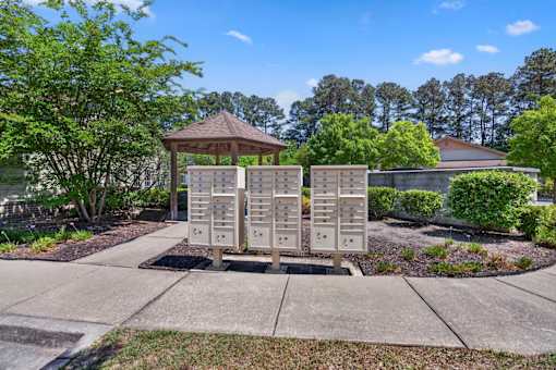 A gazebo sits in front of a row of mailboxes on a sunny day.