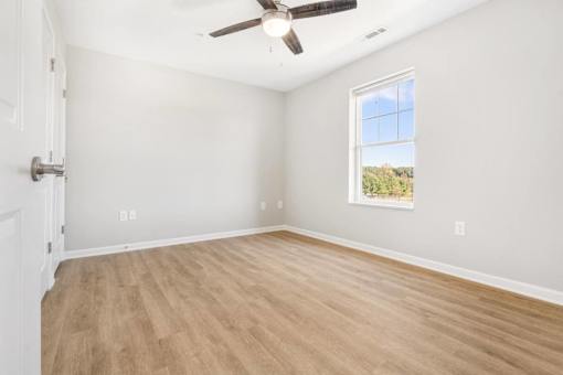 an empty living room with a ceiling fan and a window