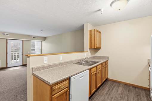 A kitchen with a white dishwasher and wooden cabinets.