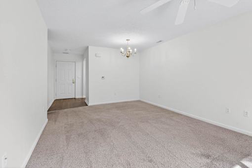 A room with a carpeted floor and a ceiling fan.