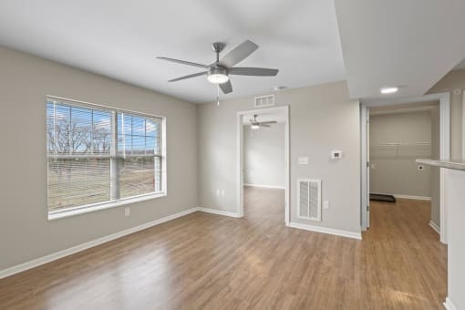 an empty living room with a ceiling fan and a window