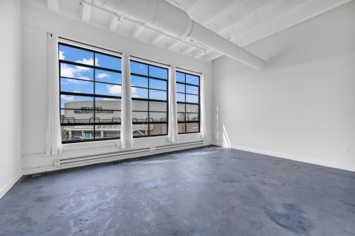 an empty room with large windows and a view of a train station