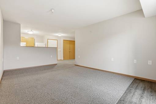 A large empty room with a carpeted floor and a door at the end.