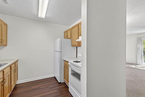 A kitchen with a white refrigerator, white oven, and wooden cabinets.