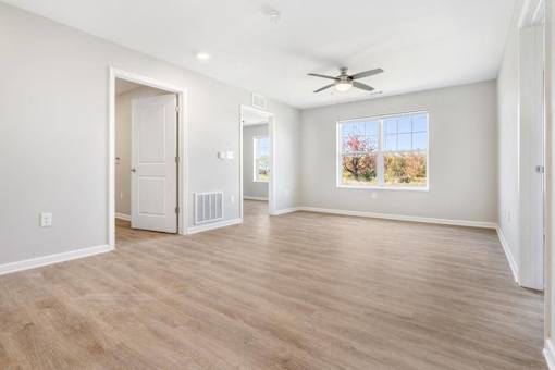 an empty living room with a ceiling fan and a window