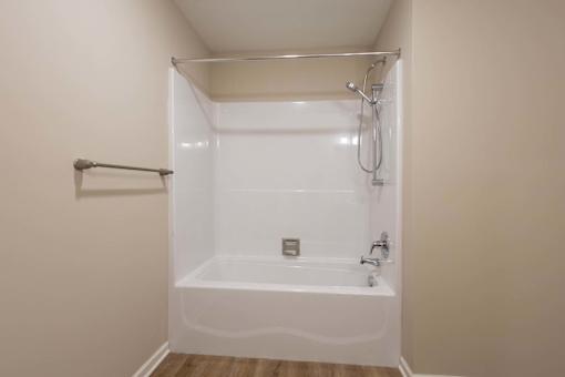 A white bathtub with a shower head and a towel bar.