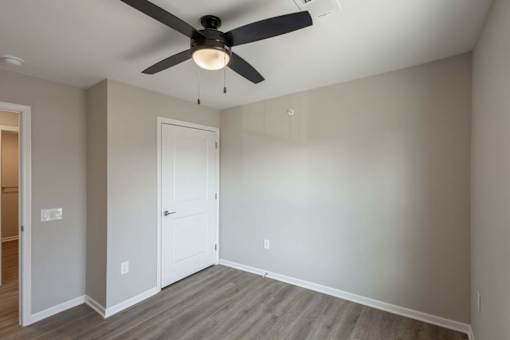 A room with a ceiling fan and a door.