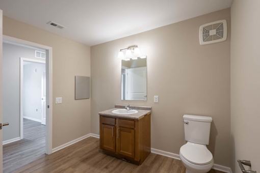 A bathroom with a toilet, sink, and mirror.