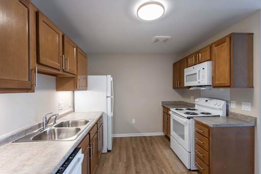 A kitchen with white appliances and wooden cabinets.