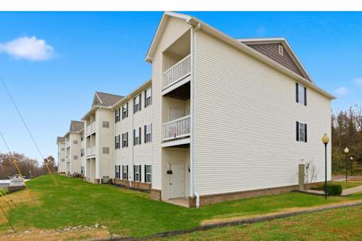 A white apartment building with a grassy front yard.