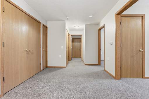 A hallway with wooden doors and carpeted flooring.