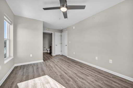 A room with a ceiling fan and wood flooring.