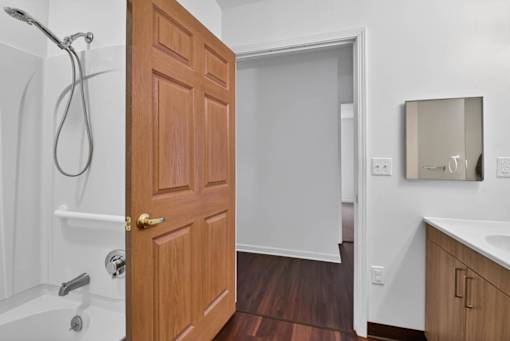A wooden door is open to a white bathroom.